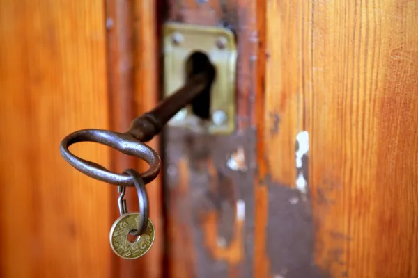 Staré dveře woth zrezivělý klíč, peset mince — Stock fotografie