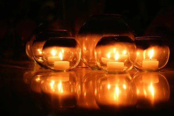 Kerzen in runden Gläsern vor schwarzem Hintergrund — Stockfoto