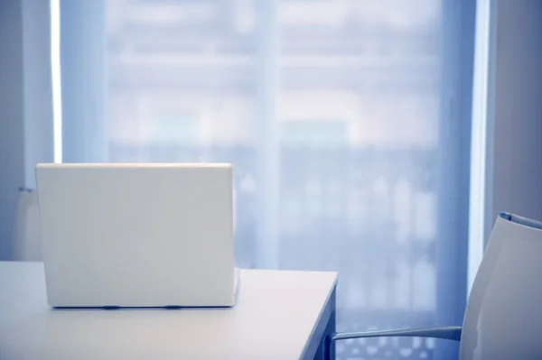 Білий ноутбук відкритий на білій кімнаті, блакитне світло — стокове фото