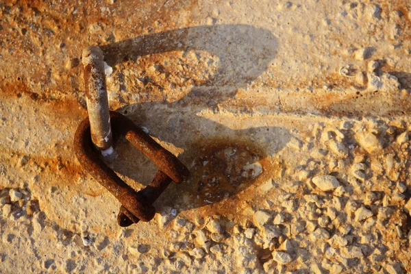 Velho grilhão enferrujado nas pedras de concreto do porto — Fotografia de Stock