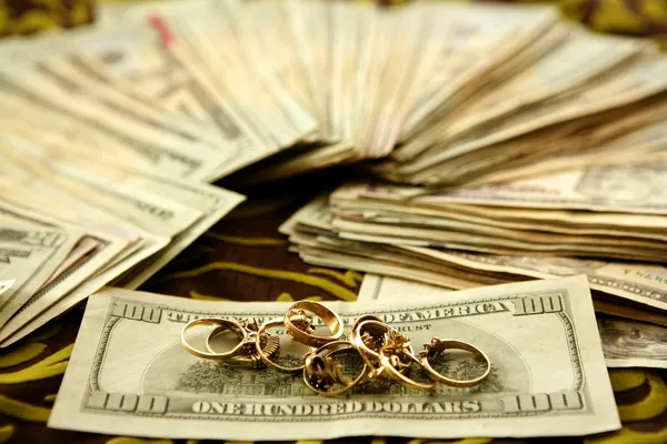 Notas de dólar e anéis de ouro sobre toalha de mesa — Fotografia de Stock