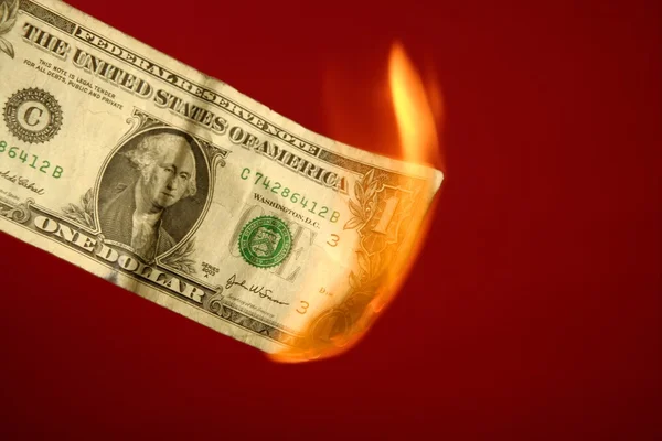 Nota di dollaro che brucia nel fuoco sul rosso — Foto Stock