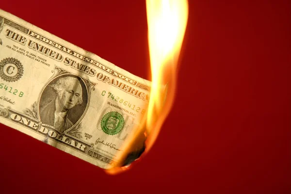 Dollar note burning in fire over red — Stock Photo, Image