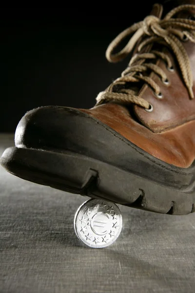 Pista de moedas em euros por uma bota — Fotografia de Stock