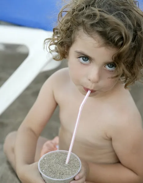 Ребенок на пляже, пьет песок — стоковое фото