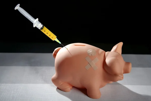 Piggy bank met spuit, financiële metafoor — Stockfoto