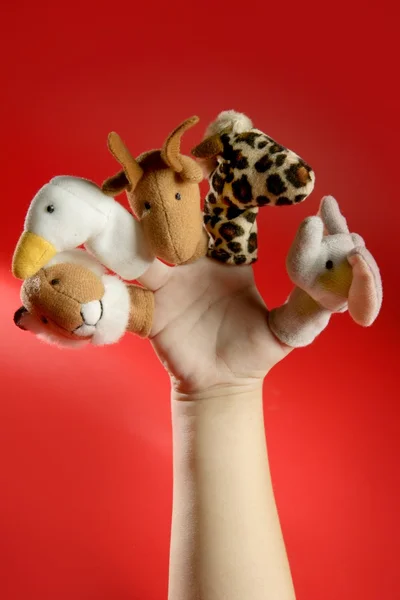 Finger puppets on a toddler hand over red — Stock Photo, Image