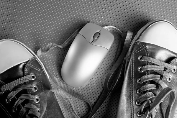 Ασημένια υπολογιστή ενσύρματο ποντίκι μεταξύ αθλητικά παπούτσια — Φωτογραφία Αρχείου