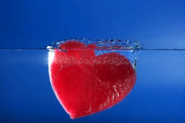 Mavi suya batan şeker kırmızı kalp şekli — Stok fotoğraf