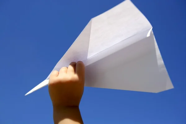 Αεροπλάνο χαρτί στο χέρι τα παιδιά πάνω από το γαλάζιο του ουρανού — Φωτογραφία Αρχείου