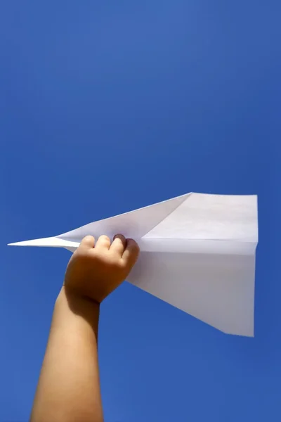 Αεροπλάνο χαρτί στο χέρι τα παιδιά πάνω από το γαλάζιο του ουρανού — Φωτογραφία Αρχείου