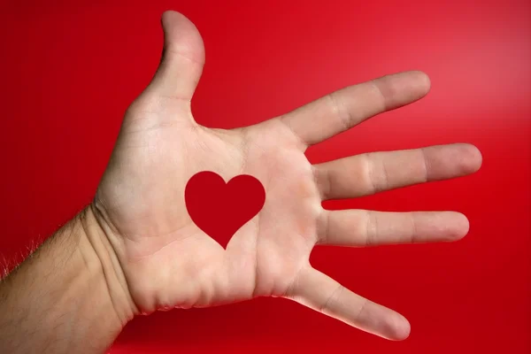 Forma di cuore rosso disegnato su una mano umana maschile — Foto Stock