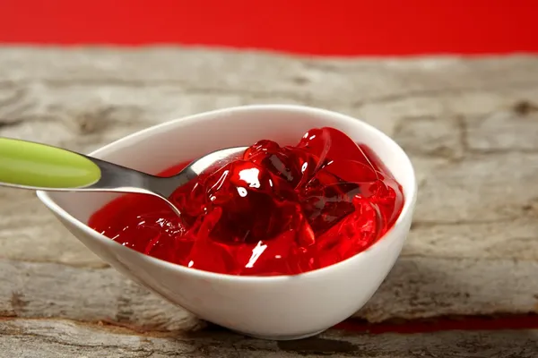 Skål med jordgubbe röd söt gelé och grön sked — Stockfoto
