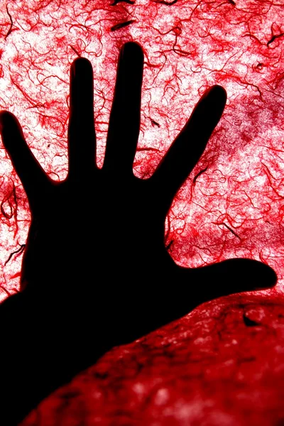 Arka plan ışığı kırmızı dokulu yüzeyi üzerinde insan elinin — Stok fotoğraf
