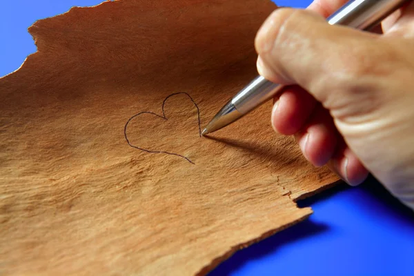 Zeichnen mit Feder ein Herz auf Holz — Stockfoto