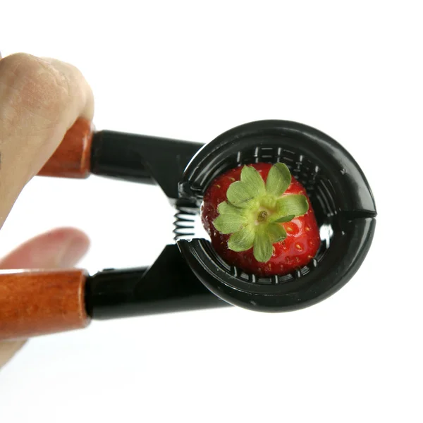 Hand pressuring a strawberry with nutcracker — Stock Photo, Image