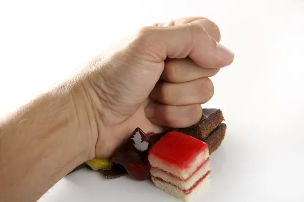 Hand hits little cakes with closed fist — Stock Photo, Image