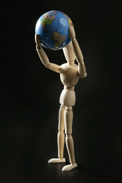 Wooden little mannequin holding the world map — Stock Photo, Image