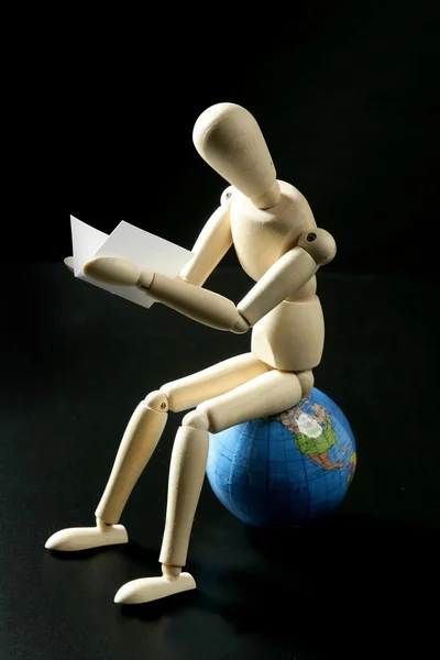 Wooden little mannequin deading sitting over the world map — Stock Photo, Image