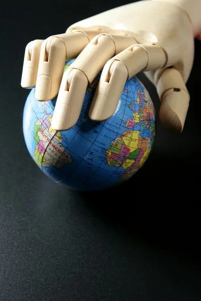 O mapa do mundo em mão manequim de madeira, backgorund preto — Fotografia de Stock