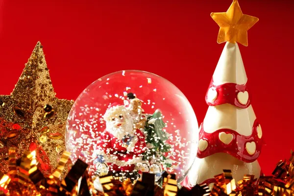 Estatuilla de Santa Claus sobre una bola de cristal nevando — Foto de Stock