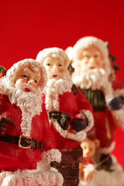 Trzy figurki Świętego Mikołaja na czerwonym tle, studio — Zdjęcie stockowe