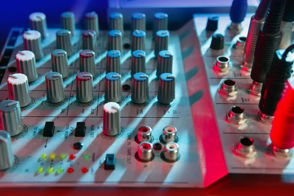 Mesa de música de mezclador de audio bajo luces coloridas —  Fotos de Stock