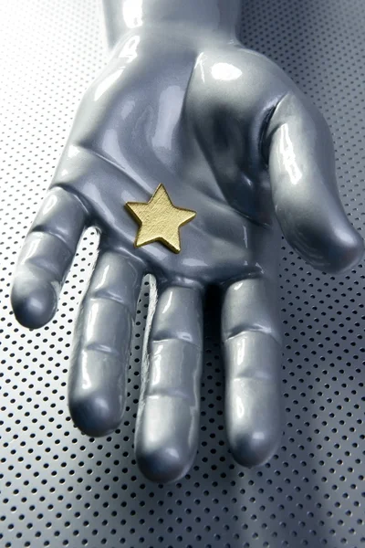 Zlatá hvězda na stříbrné futuristické ruku — Stock fotografie