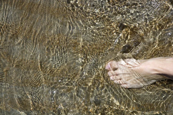 Pláž turistického nohy chůzi na břeh mělké vodě — Stock fotografie