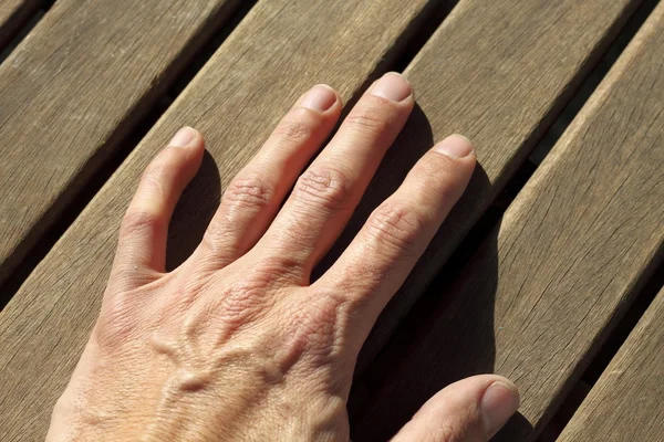 Homem mão sobre ensolarado teca madeira linhas — Fotografia de Stock