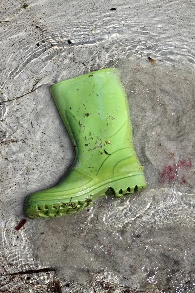 Πράσινο μπότες σκουπίδια στην παραλία ακτή ρύπανσης — Φωτογραφία Αρχείου