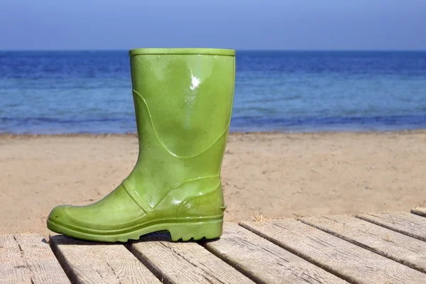 Stivale verde sulla spiaggia sfortunato pescatore metafora — Foto Stock