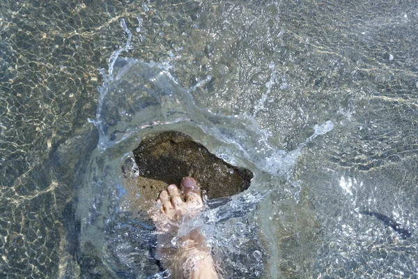 Stříkající vody turistické nohy na pláži pobřeží — Stock fotografie