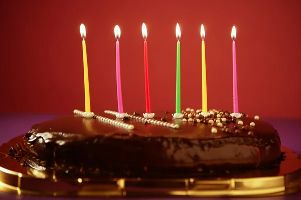 Kleurrijke birthday licht kaarsen in chocolade taart — Stockfoto