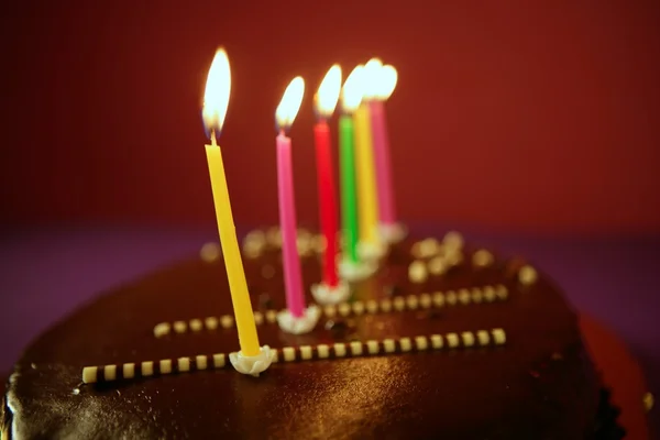 Velas coloridas da luz do aniversário no bolo de chocolate — Fotografia de Stock