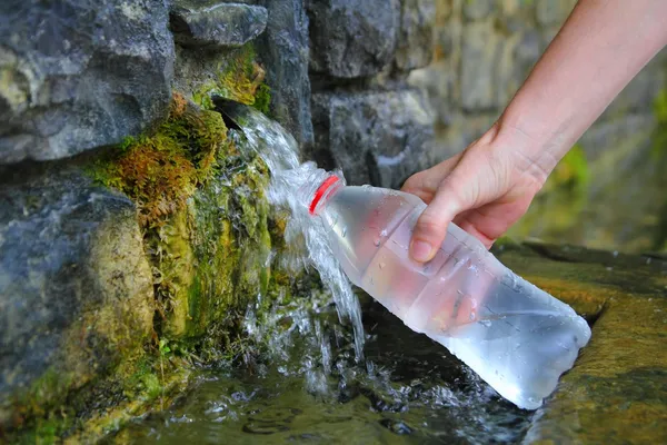Źródłem wiosna woda butelkować napełniania ręka — Zdjęcie stockowe