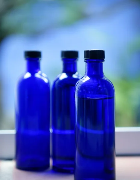 Три бутылки масла для тела из голубого стекла — стоковое фото