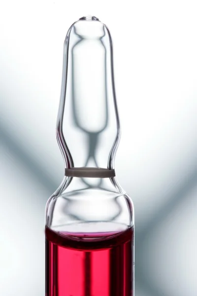 Glass ampoule with red liquid medicine — Stock Photo, Image