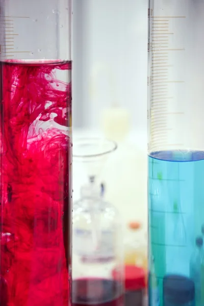 Laboratóriumi cuccok, üveghengerbe, színes folyadékok — Stock Fotó
