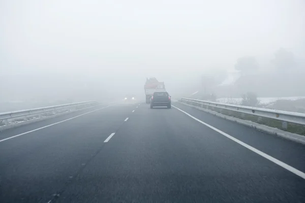 Carretera gris brumosa, coches conduciendo hacia la niebla — Foto de Stock