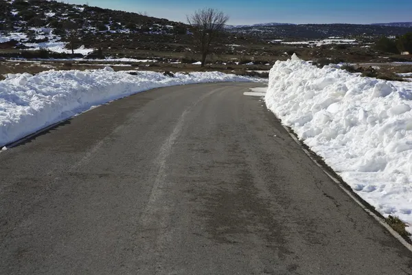 Curva de estrada de asfalto com neve em ambas as bordas laterais — Fotografia de Stock
