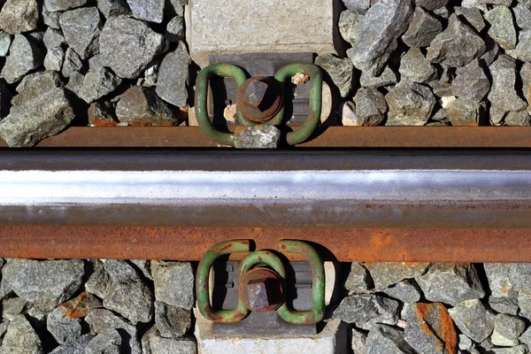 Железные ржавые железнодорожные детали над темными камнями — стоковое фото