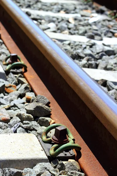 Ferrocarril de hierro oxidado detalle sobre piedras oscuras —  Fotos de Stock