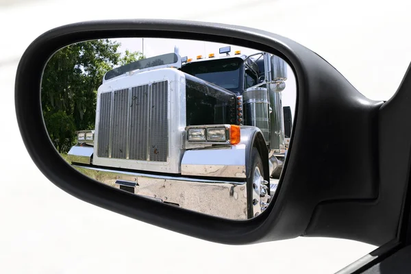 Зеркало заднего вида автомобиля, обгоняющего большой грузовик — стоковое фото