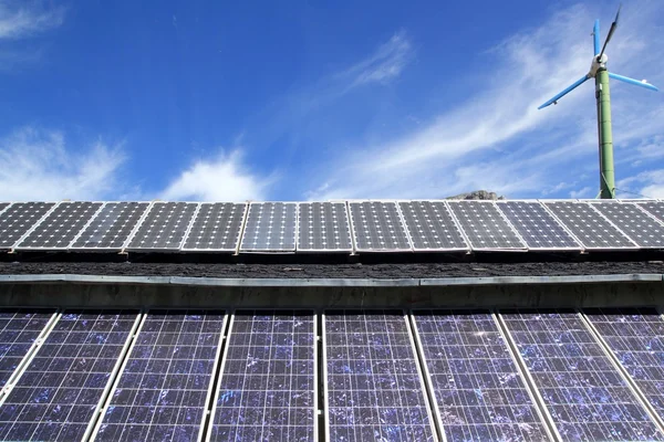 太陽電池板と青い空の下で風車 — ストック写真