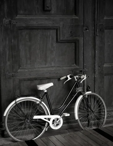 Bicicleta preta vintage envelhecida, grande porta de madeira, preto e branco — Fotografia de Stock