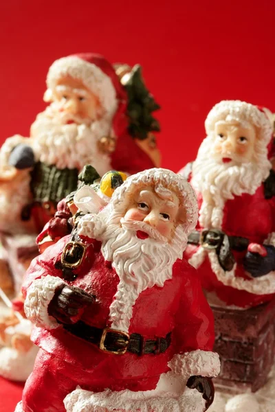 Tres figuras de Santa Claus sobre fondo rojo, estudio —  Fotos de Stock