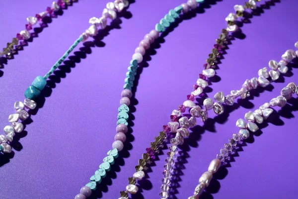 Collane gioielli pietre di colore, sfondo viola — Foto Stock