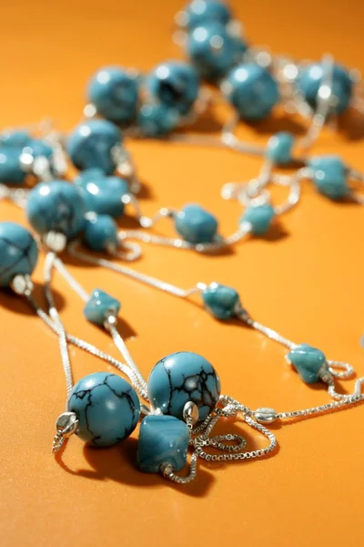 Tyrkysové náhrdelníky oranžové pozadí — Stock fotografie