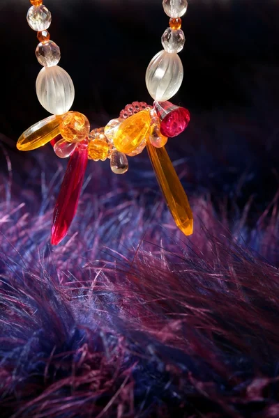 青い紫色の羽の上のオレンジ色の宝石ネックレス — ストック写真